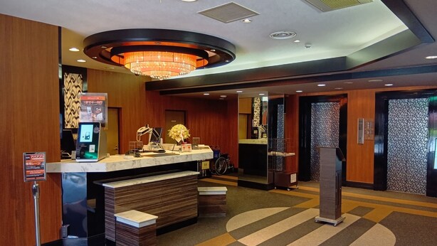 Zona de recepción de un hotel con mostrador de mármol, candelabro y acceso para sillas de ruedas.