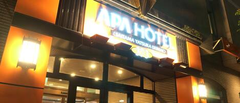 A hotel entrance with a prominent sign reading "APA HOTEL" and a number "373".