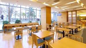 A spacious dining area with wooden tables and chairs, large windows offering a view of the outdoors, and a modern ceiling design. - Natural Hot Spring Dormy Inn Premium Kushiro (Kushiro)