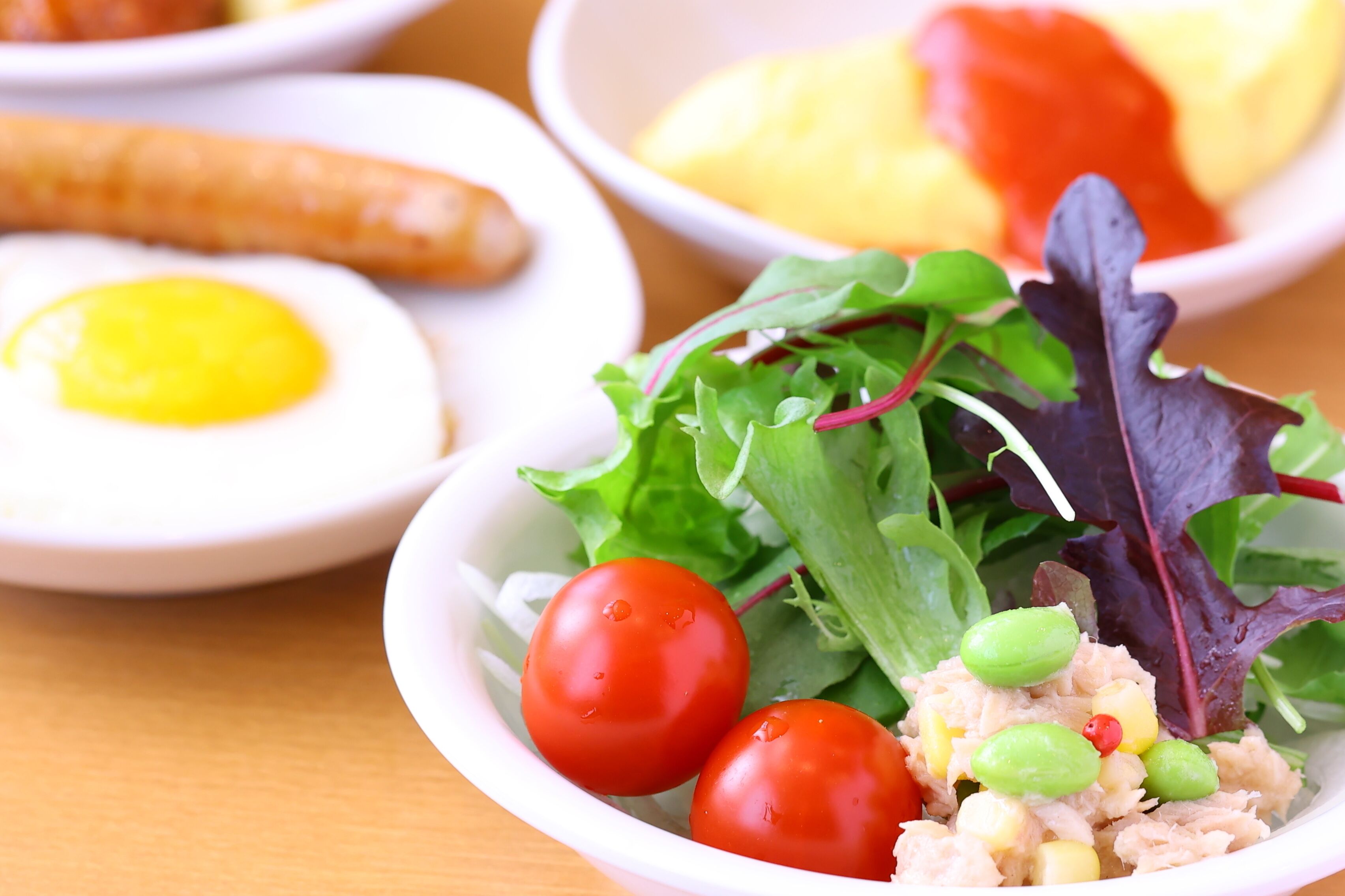 A bowl of salad with lettuce, cherry tomatoes, and green peas.