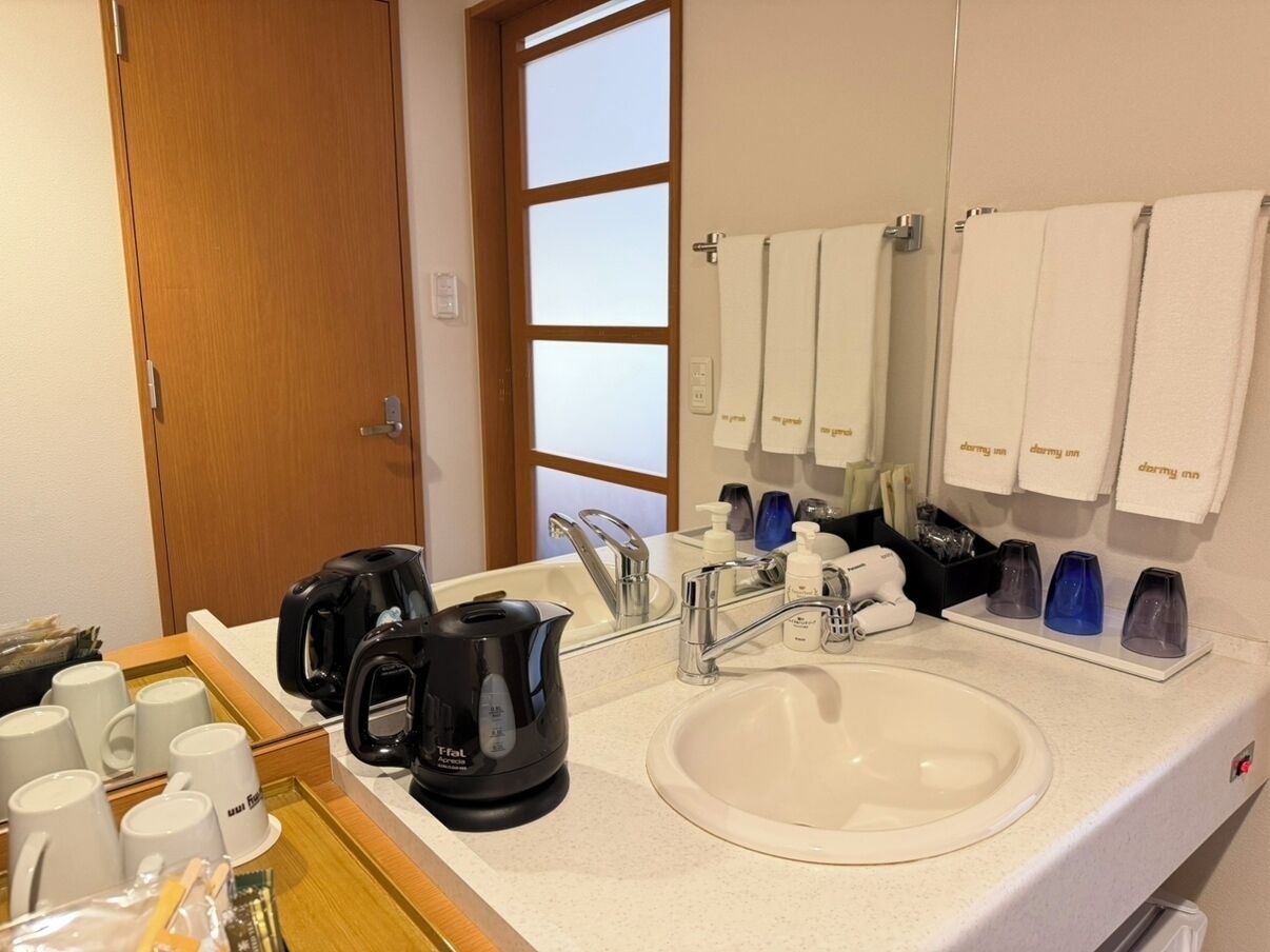 A hotel bathroom with a sink, mirror, and towel rack.