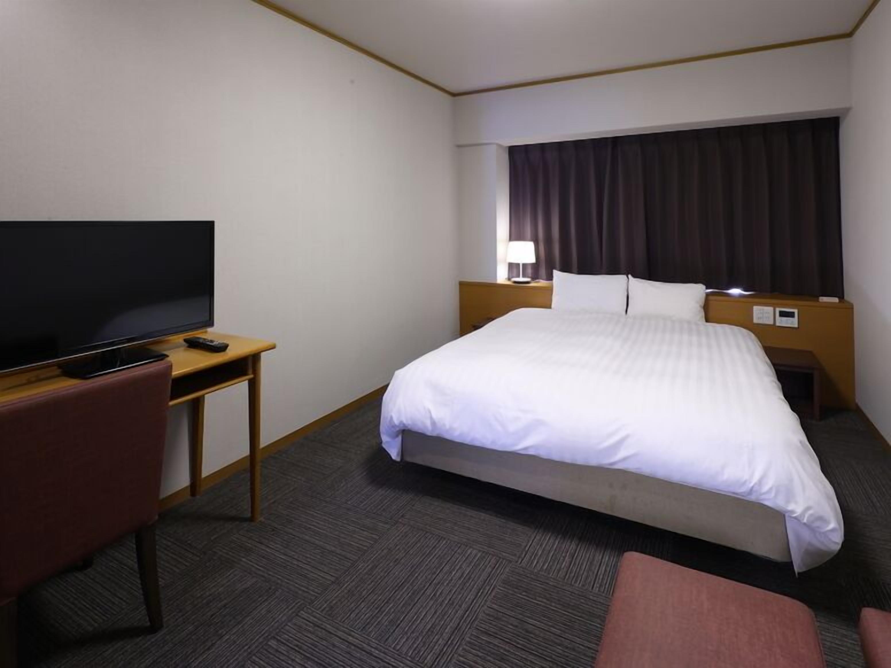Une chambre d’hôtel avec un lit, une télévision, un bureau et une chaise.