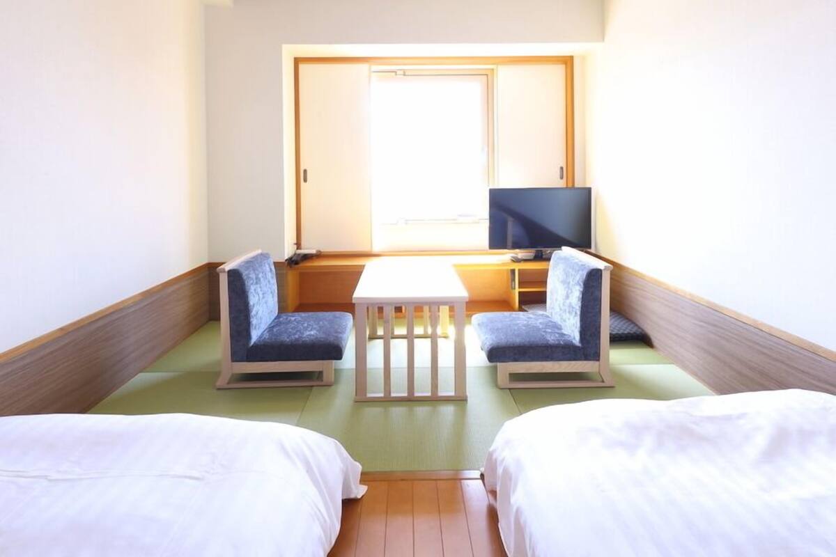 A hotel room with two beds, a television, and a small table.