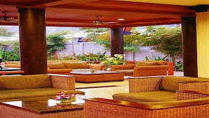 A spacious indoor seating area with wicker furniture and a glass coffee table. - Kata Poolside Resort (Karon)