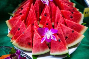 A plate of watermelon slices arranged in a triangular pattern, with a purple orchid in the center.