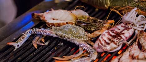 A grill with seafood, including lobsters and crabs, being cooked.
