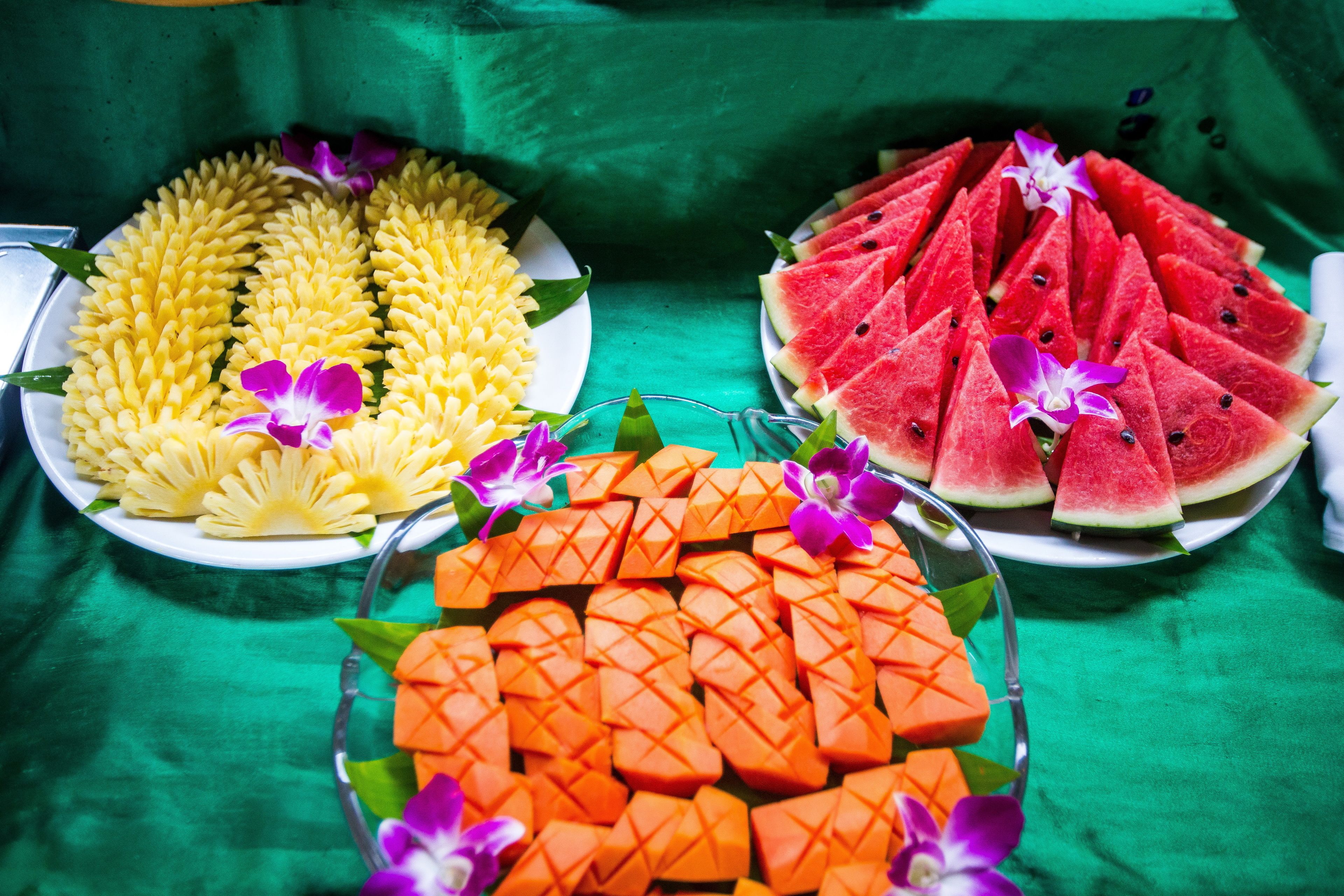 Una mesa con tres platos de fruta dispuesta en un diseño decorativo.