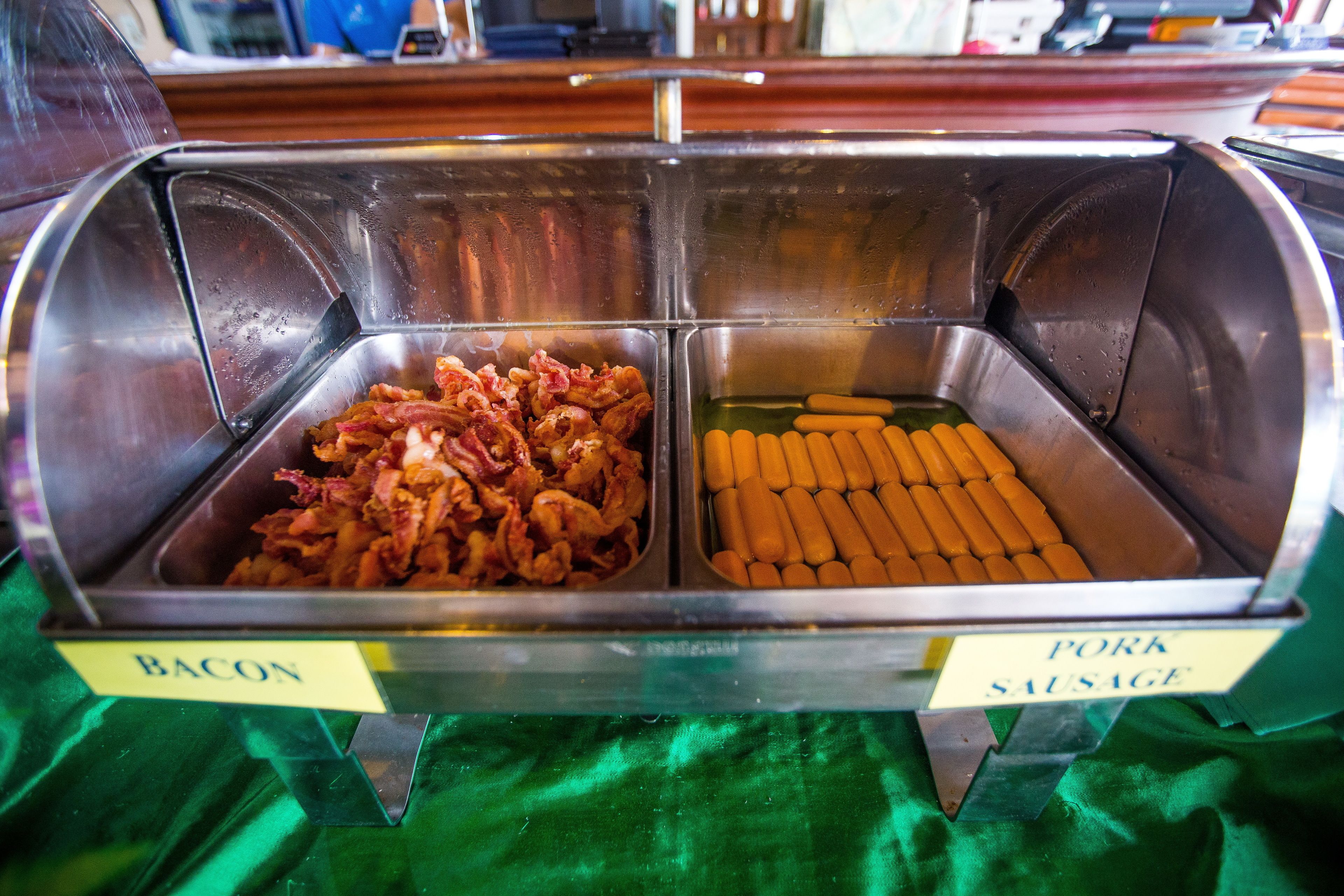 A buffet with labeled sections for bacon and pork sausage.