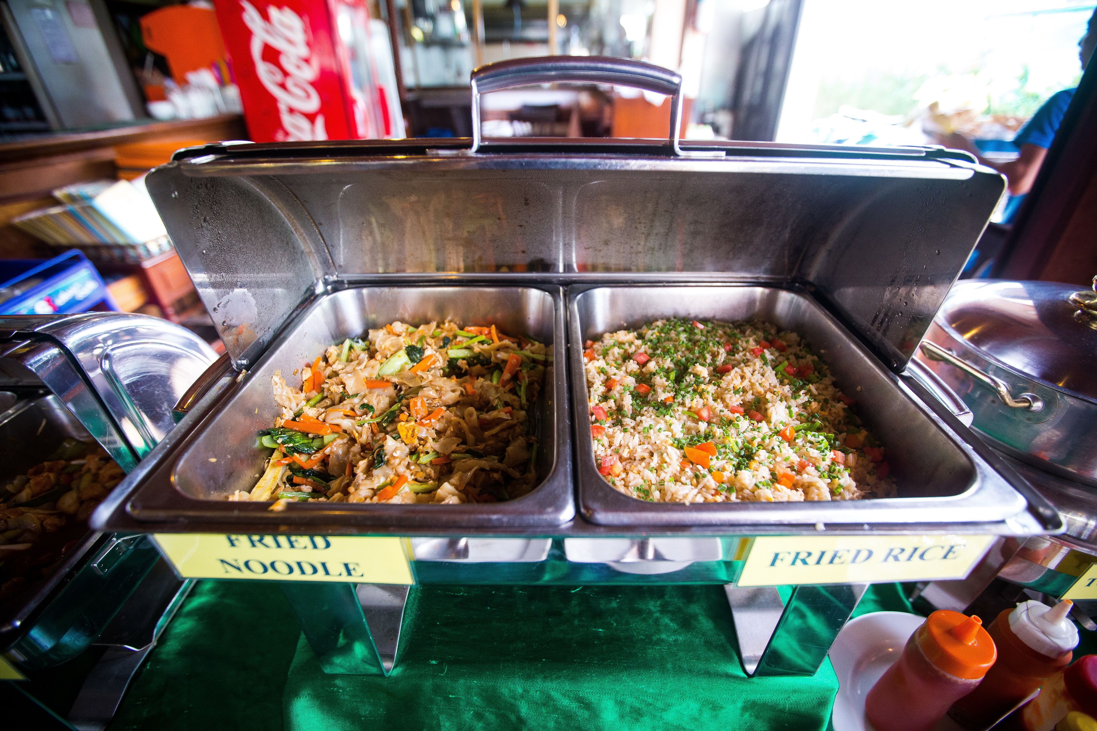 A buffet with labeled containers of fried noodles and fried rice.