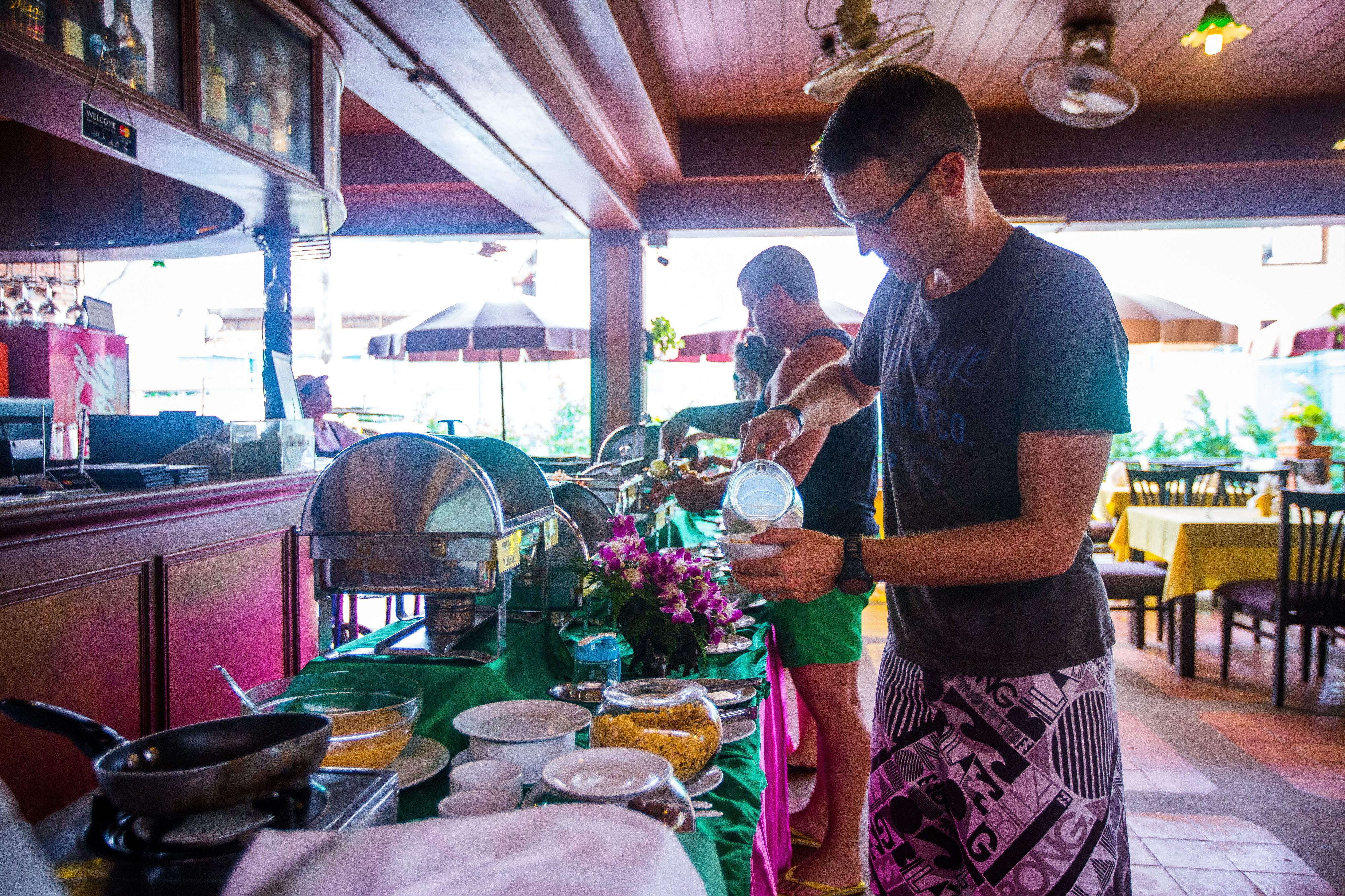 A buffet setup with various food items and a person serving food.