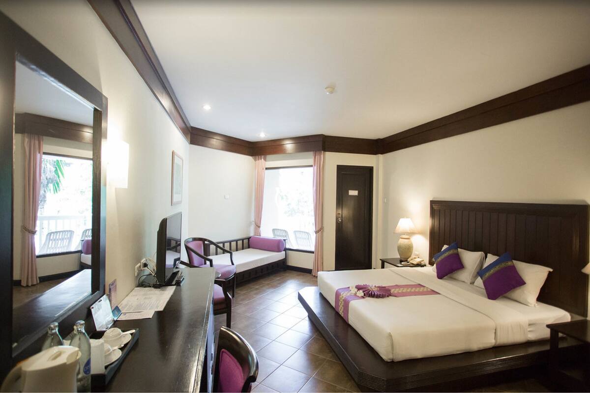 Ein Hotelzimmer mit Bett, Schreibtisch, Stuhl und einem großen Fenster.