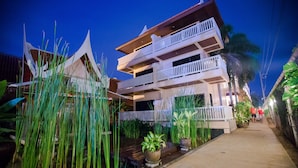 A multi-story building with balconies, a pathway, and potted plants. - Kata Poolside Resort (Karon)
