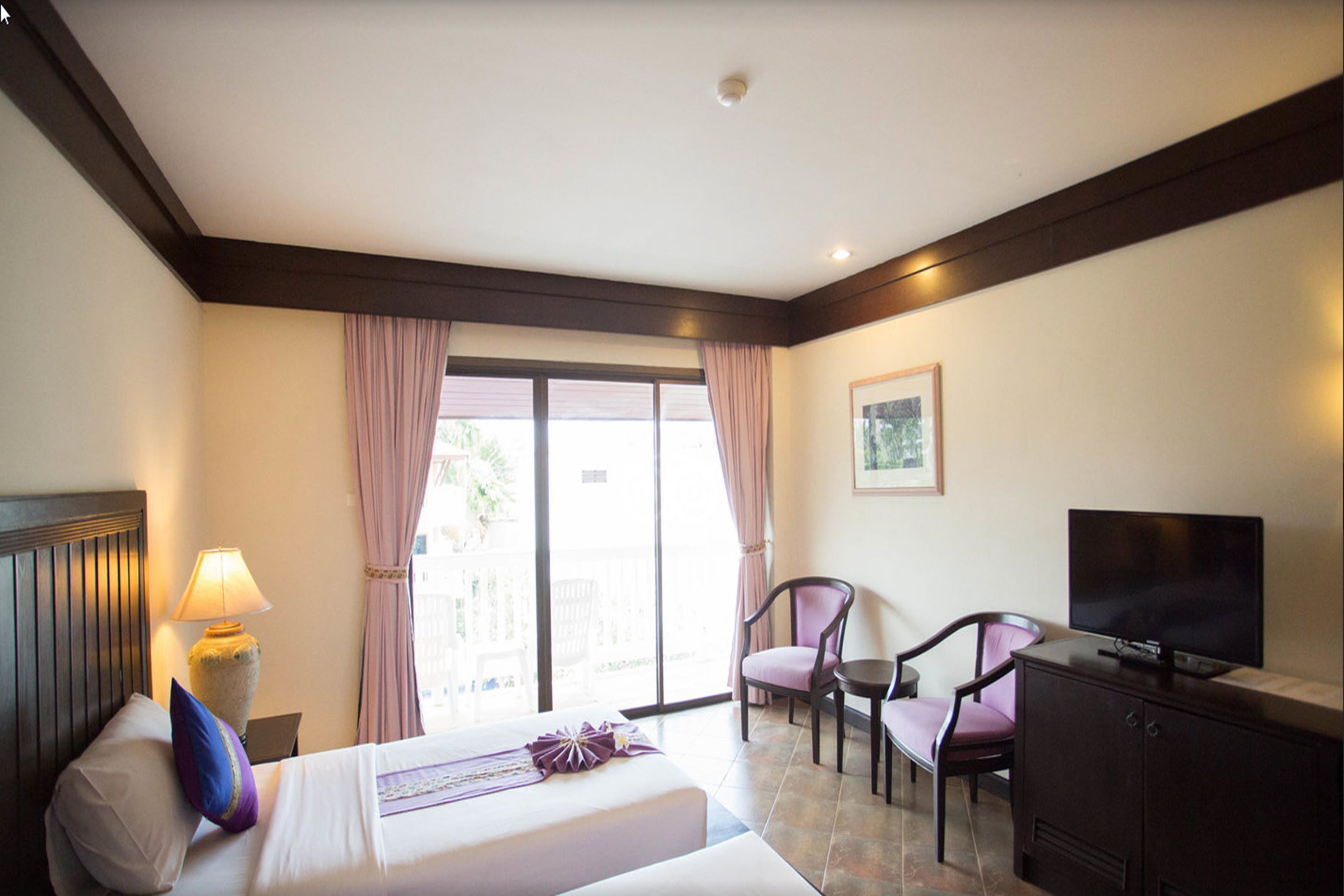 A hotel room with a bed, a desk, a chair, a television, and a window with curtains.