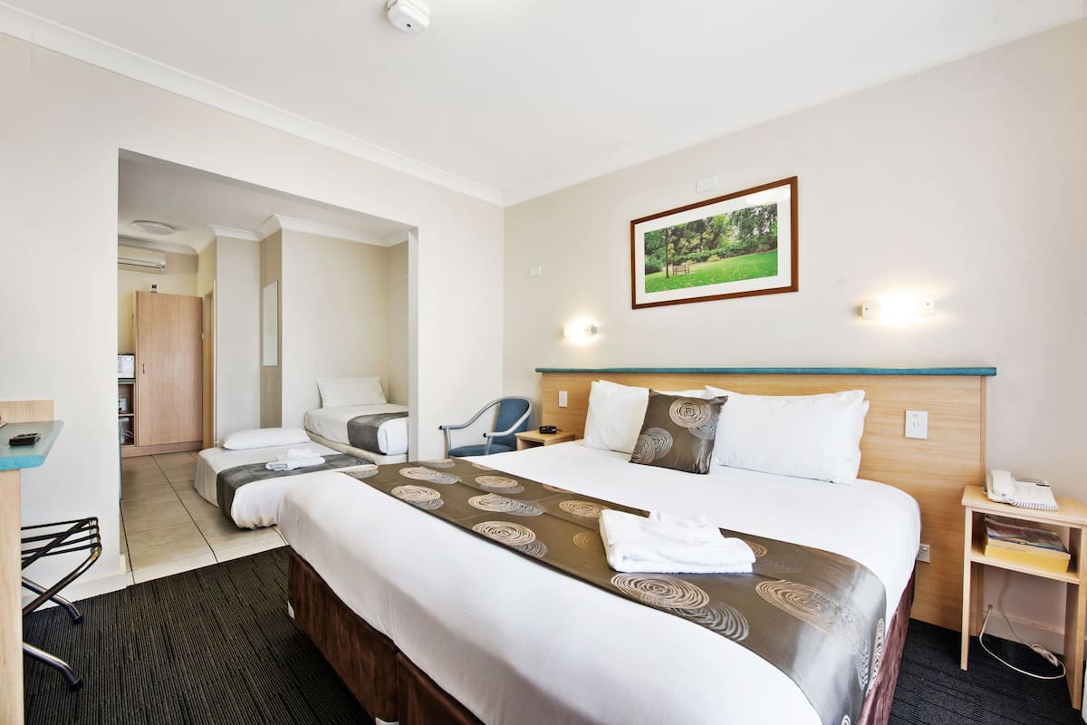 A hotel room with a large bed, a desk, a chair, and a small table with a phone.