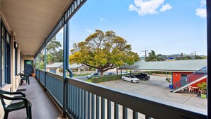 A balcony with a view of a parking lot, a tree, and a building with a red exterior. - Welcome Inn 277 (Frewville)