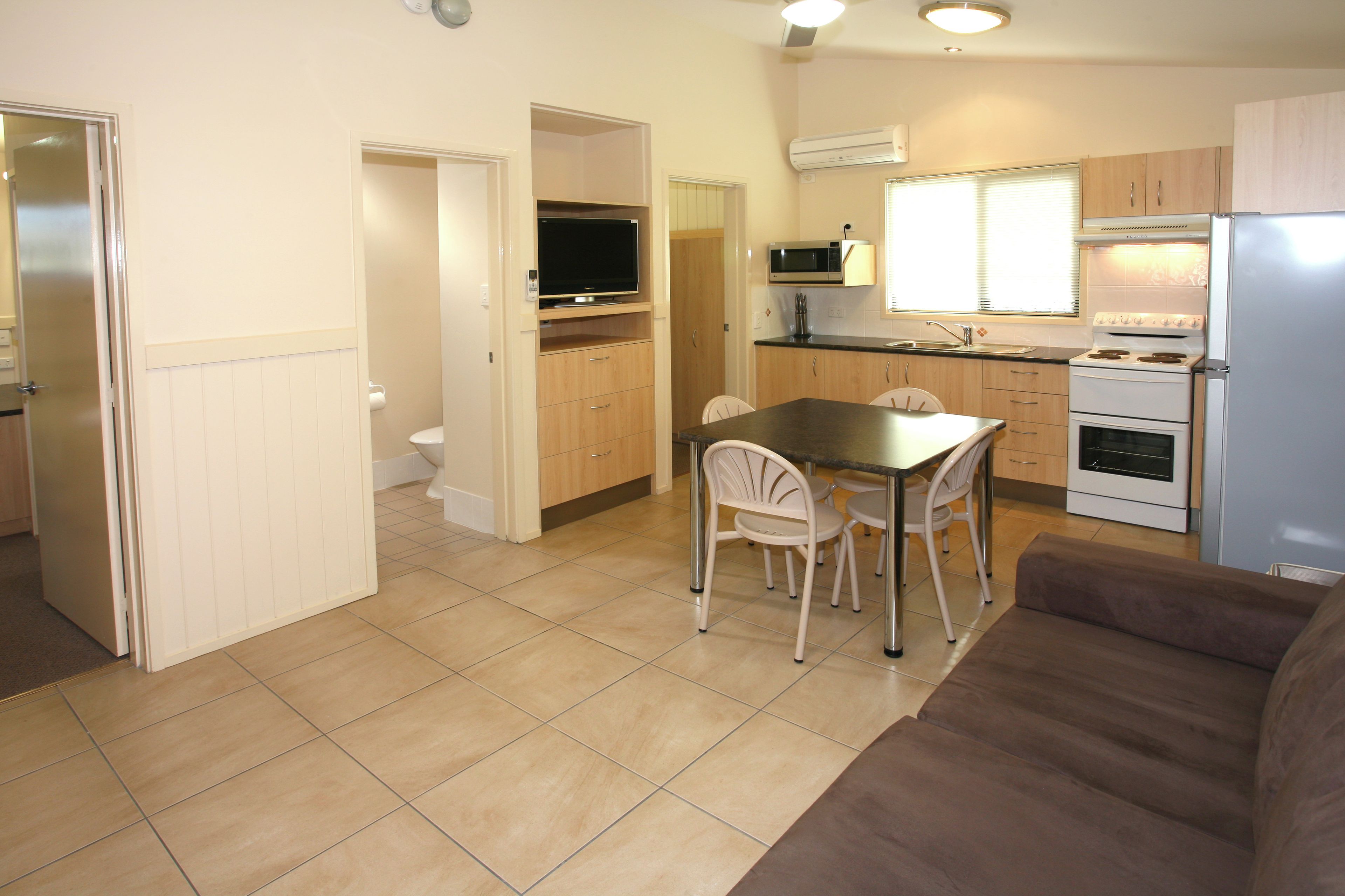 A compact kitchen with a dining area, a sofa, and a television.