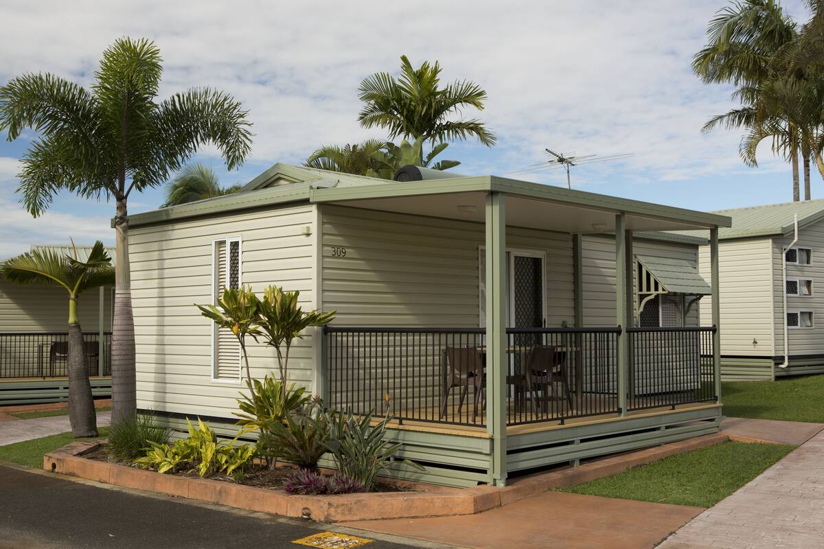 A small, single-story building with a porch and a small garden area.