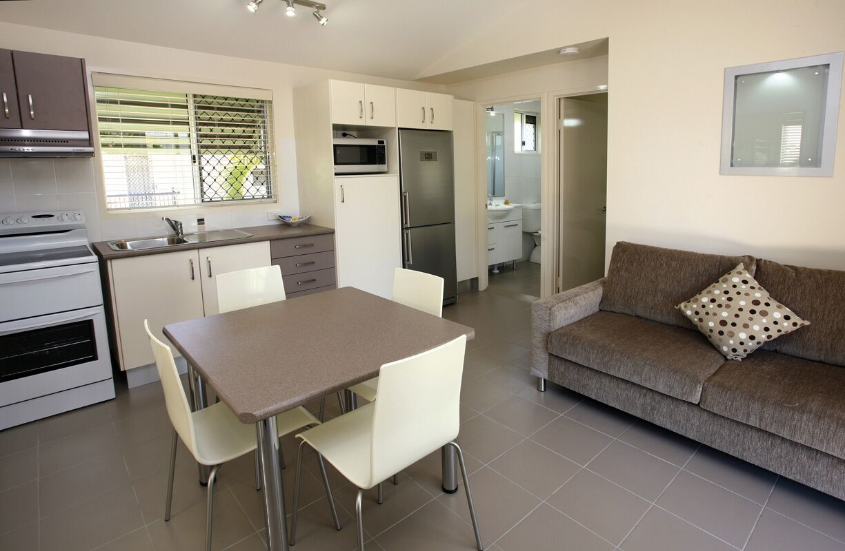 Cocina compacta con una mesa y sillas, un sofá y un refrigerador.