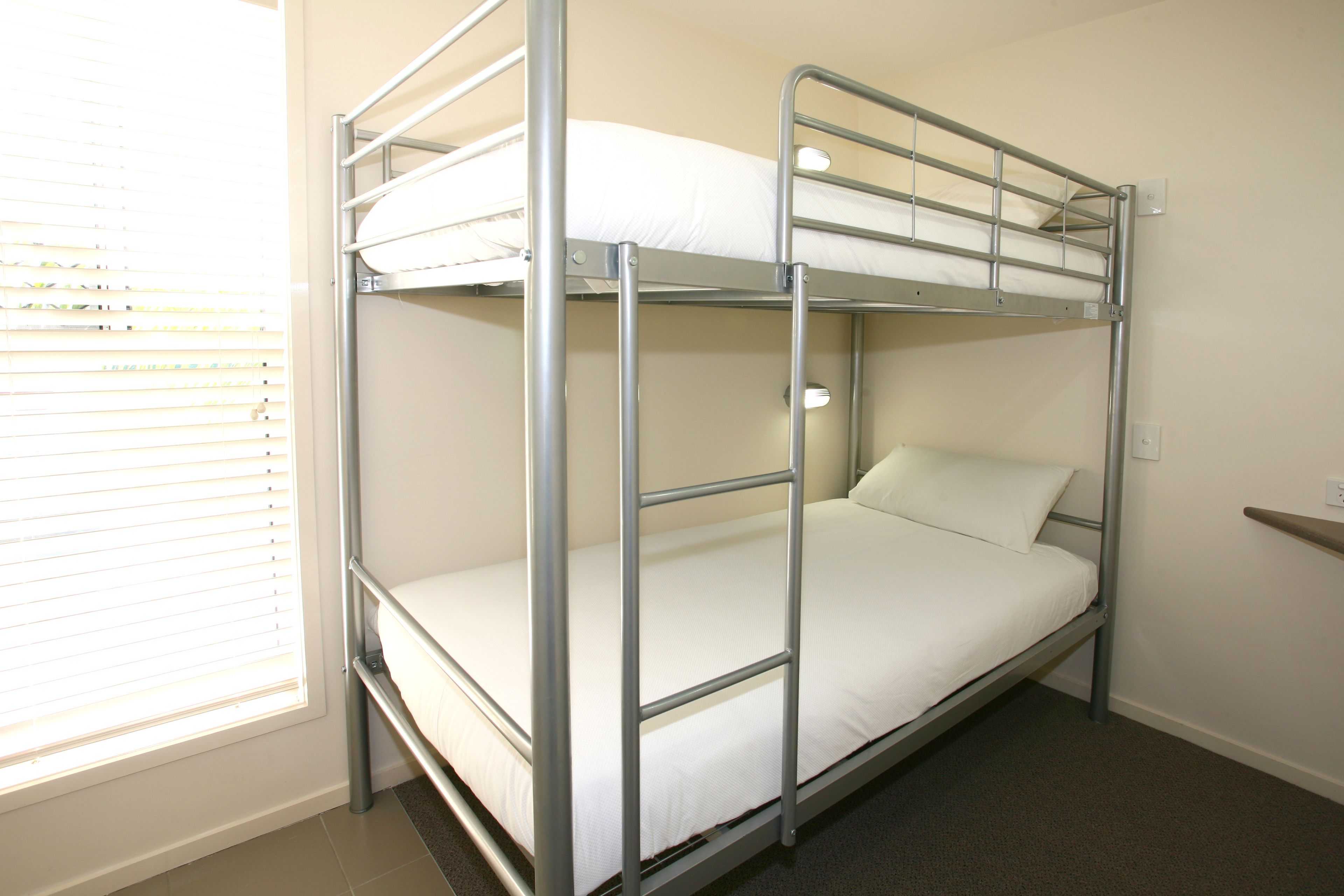 A bunk bed with a metal frame and white bedding.