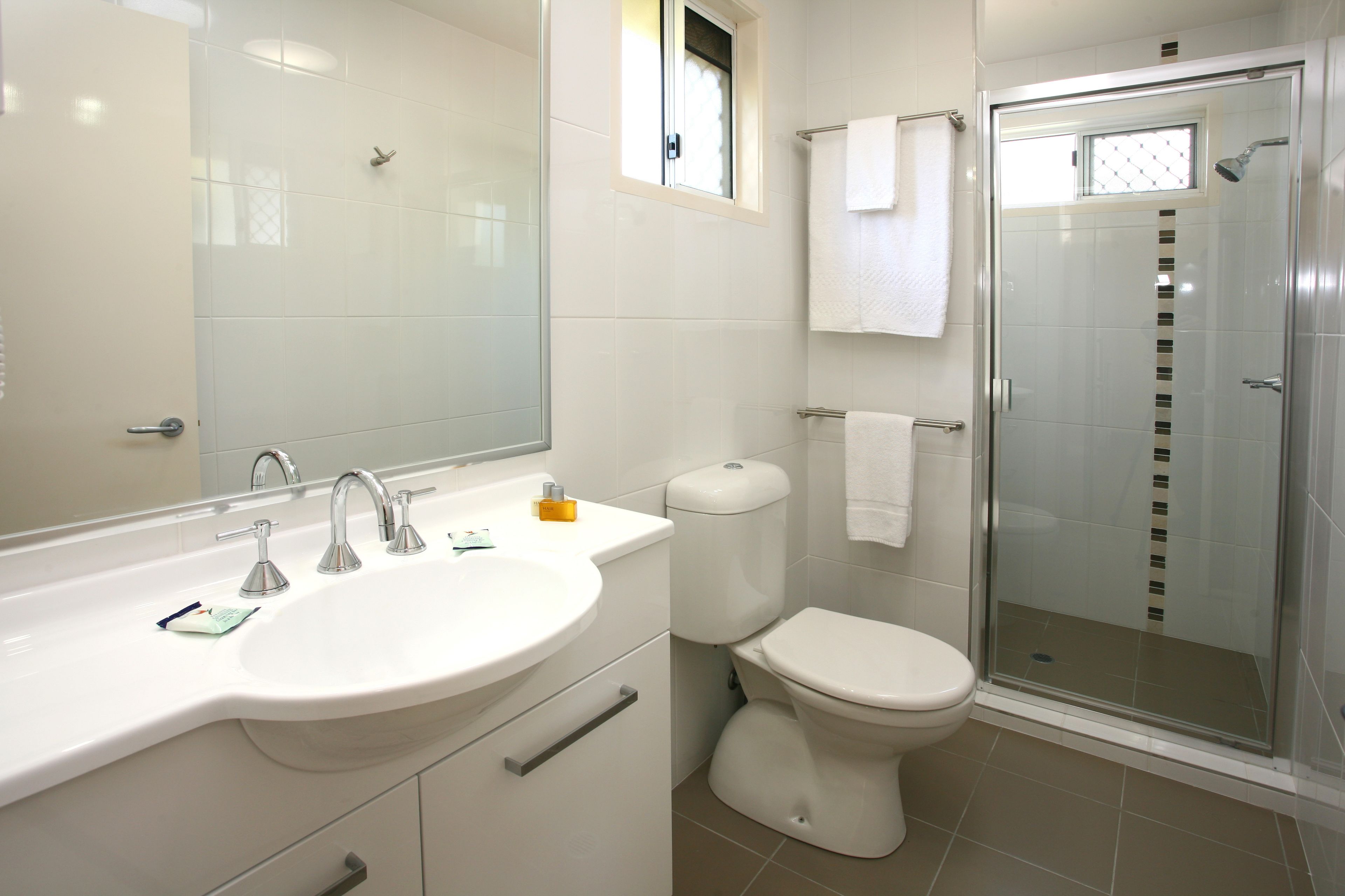 Un bagno moderno con lavandino, specchio, WC e cabina doccia in vetro.