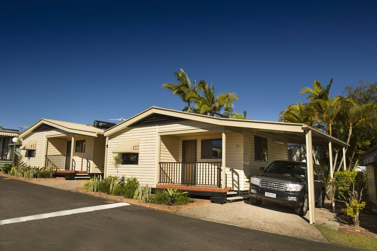 A row of single-story mobile homes with a car parked in front.