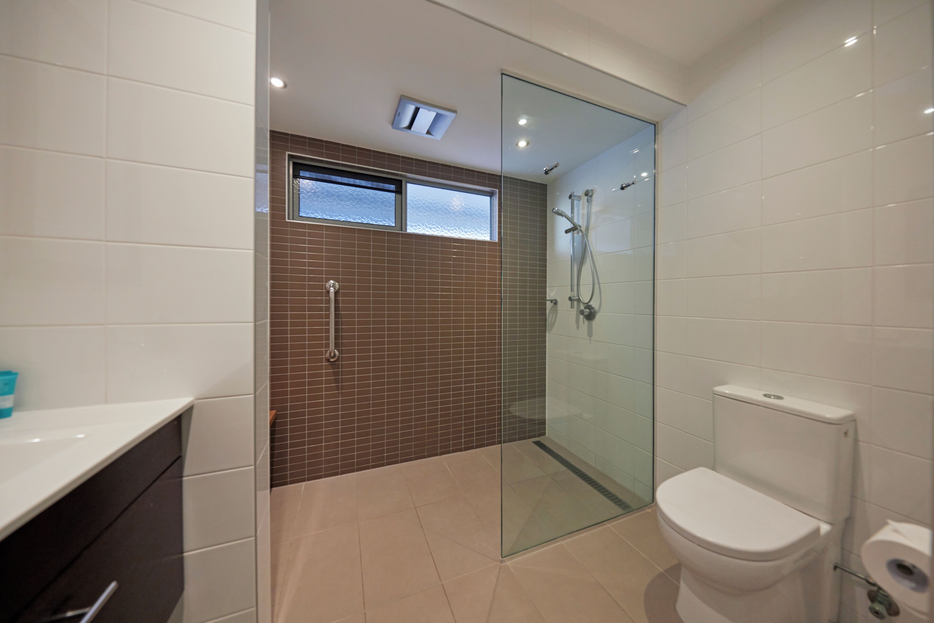 A modern bathroom with a glass-enclosed shower, a toilet, and a sink.