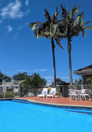 Una piscina al aire libre, sillones reclinables de piscina
