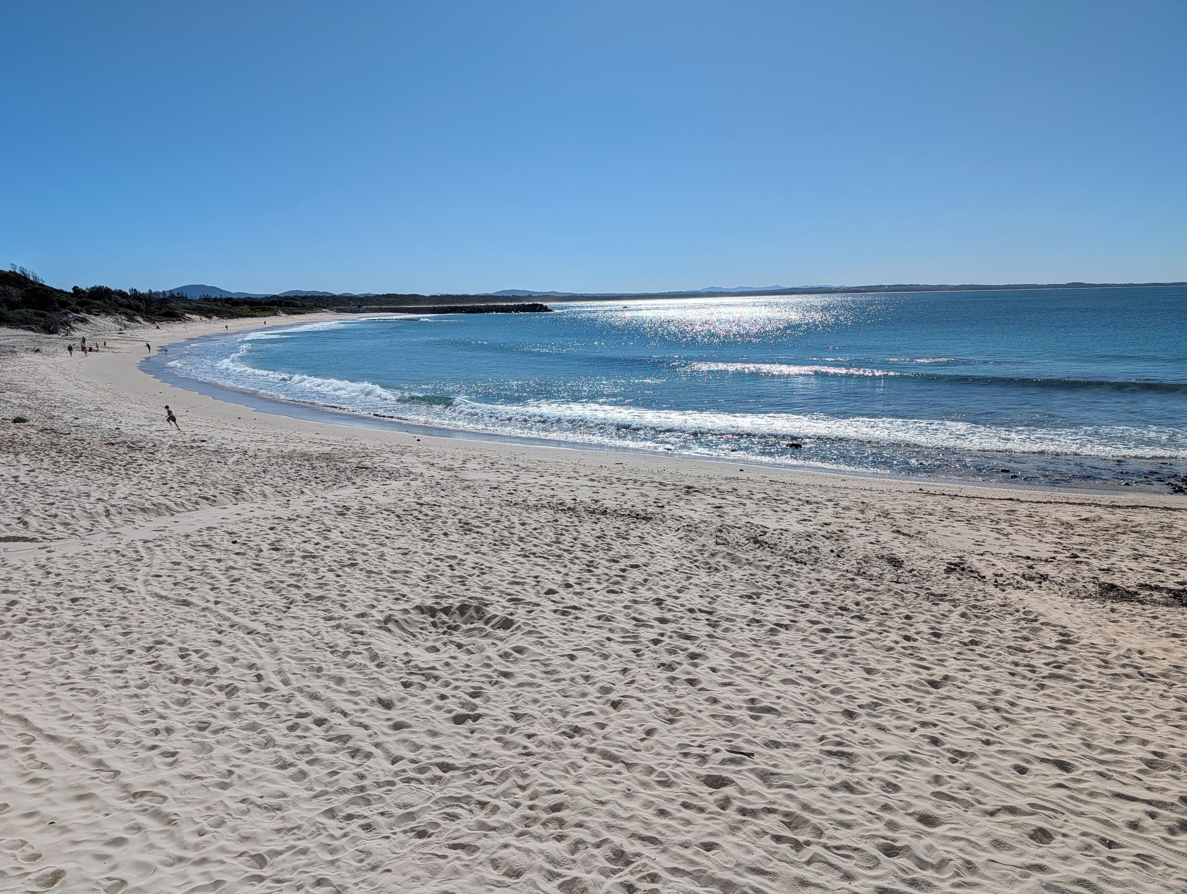 A sandy beach with gentle waves and a clear sky.