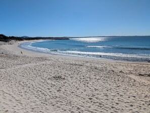 A sandy beach with gentle waves and a clear sky.