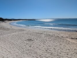 A sandy beach with gentle waves and a clear sky.