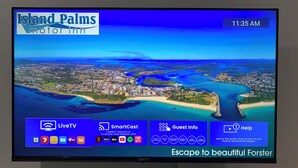Pantalla de hotel con transmisión en vivo de un pueblo costero, menú SmartCast e información para huéspedes.