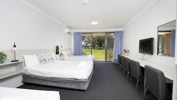 A hotel room with a bed, a desk, a TV, and a view of the outdoors.