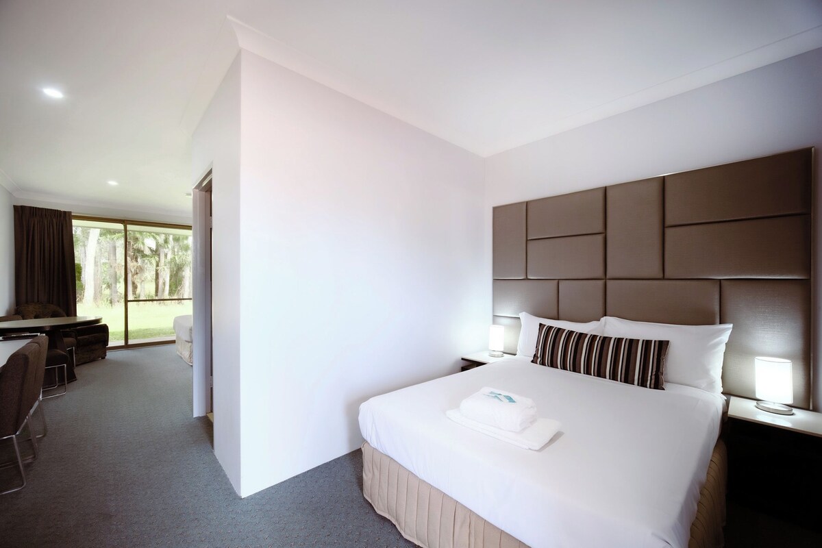 A hotel room with a large bed, a desk, and a view of the outdoors.