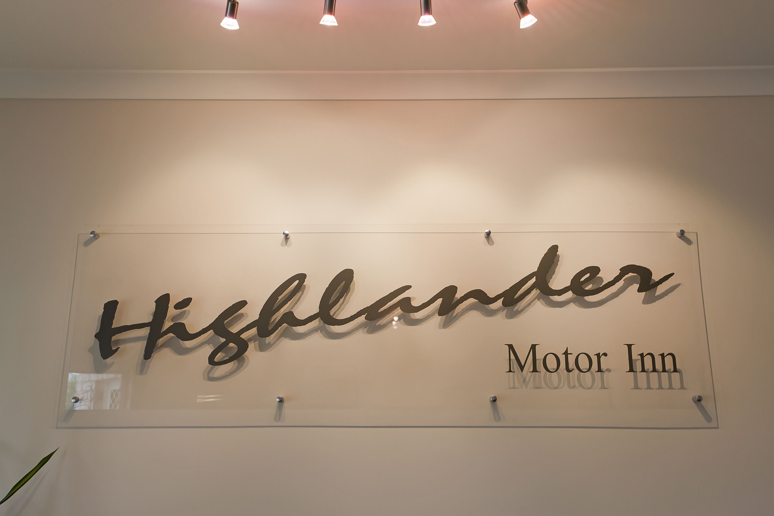 A sign with the name "Highlander Motor Inn" on a wall.