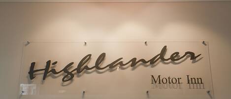 A sign with the name "Highlander Motor Inn" on a wall.