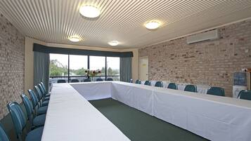 A conference room with a long table, chairs, a brick wall, and a large window.
