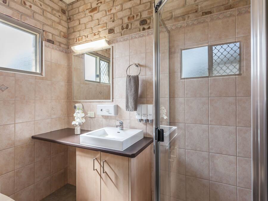 A bathroom with a large sink, a glass shower enclosure, and a mirror above the sink.
