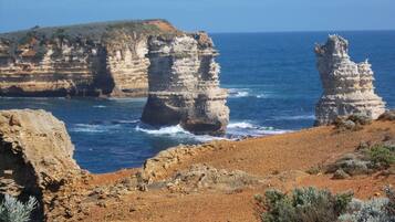 A coastal landscape with rocky cliffs and a clear blue sea.