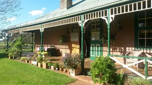 A building with a covered porch, outdoor seating, and potted plants. - Butterfly Farm (Nirranda)