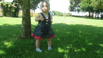 Un niño de pie sobre césped, con árboles y una cerca al fondo.
