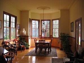 A dining area with wooden furniture, large windows, and a chandelier.