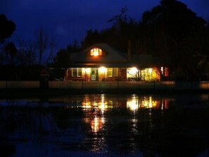 A house with a visible front porch and a reflection in the water.
