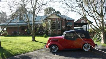 A vintage red convertible car parked in front of a building with a green roof and a sign that reads "RECEPTION".