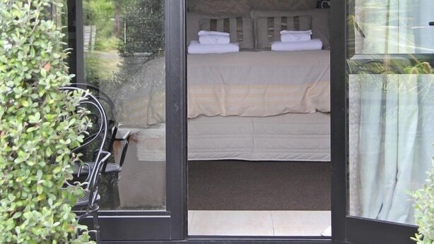 A bedroom with a bed, a chandelier, and a view of greenery outside. - Cambridge Coach House (Cambridge)