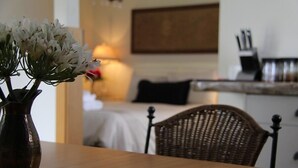 A dining area with a wooden table and a wicker chair. A vase with flowers is on the table. - Cambridge Coach House (Cambridge)