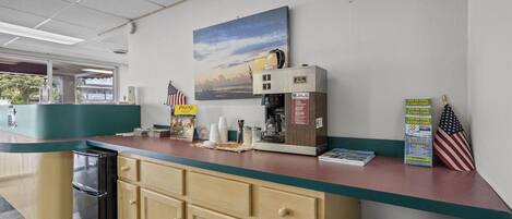 A counter with a coffee machine, a painting of a sunset, and a sign for a seafood restaurant.