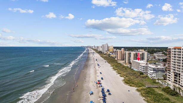 A coastal hotel with multiple floors, a beach view, and a prominent 'HOME' sign on one building. - Oasis Hotel (North Myrtle Beach)
