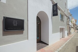 Un edificio con un letrero que dice "HOTEL SAN MIGUEL" y un arco que da acceso a una puerta.