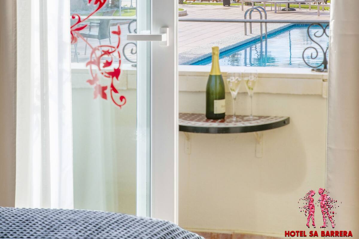 Une chambre avec vue sur une piscine et un espace salon extérieur.