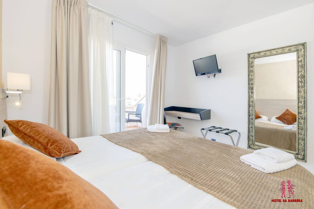 Une chambre d’hôtel avec un lit, une télévision, un grand miroir et une vue sur l’extérieur.